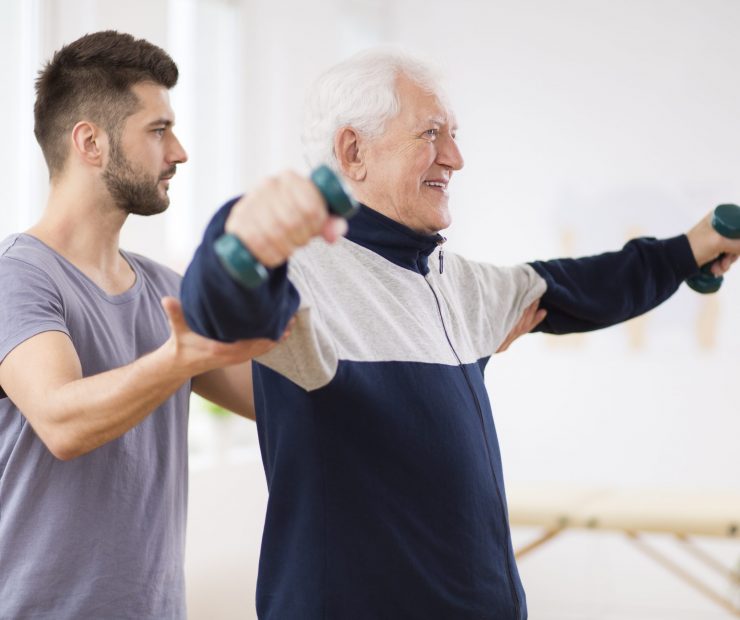 Senior man after stroke at nursing home exercising with professional physiotherapist